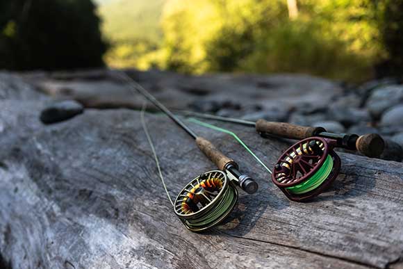 Two fly fishing rods on a log - Pacific Rover Fly Fishing Concierge service.